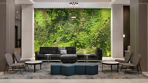A modern lobby with a green wall, seating area, and a chandelier. - Embassy Suites by Hilton Atlanta Midtown (Atlanta)