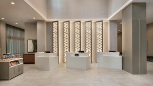 A reception area with a modern design, featuring a reception desk, a counter, and a decorative partition with geometric patterns. - Embassy Suites by Hilton Atlanta Midtown (Atlanta)