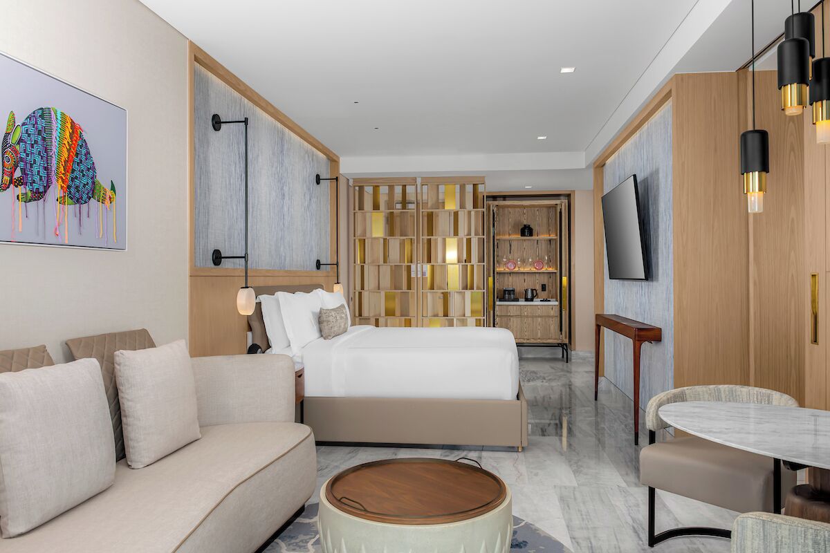 Une chambre d’hôtel moderne équipée d’un lit, d’un canapé, d’une table à manger et d’un téléviseur.
