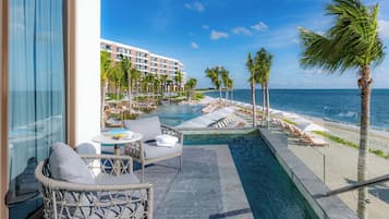 A balcony with a view of a pool, beach, and hotel buildings.