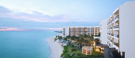 A beachfront hotel with multiple buildings, a pool area, and a view of the ocean.
