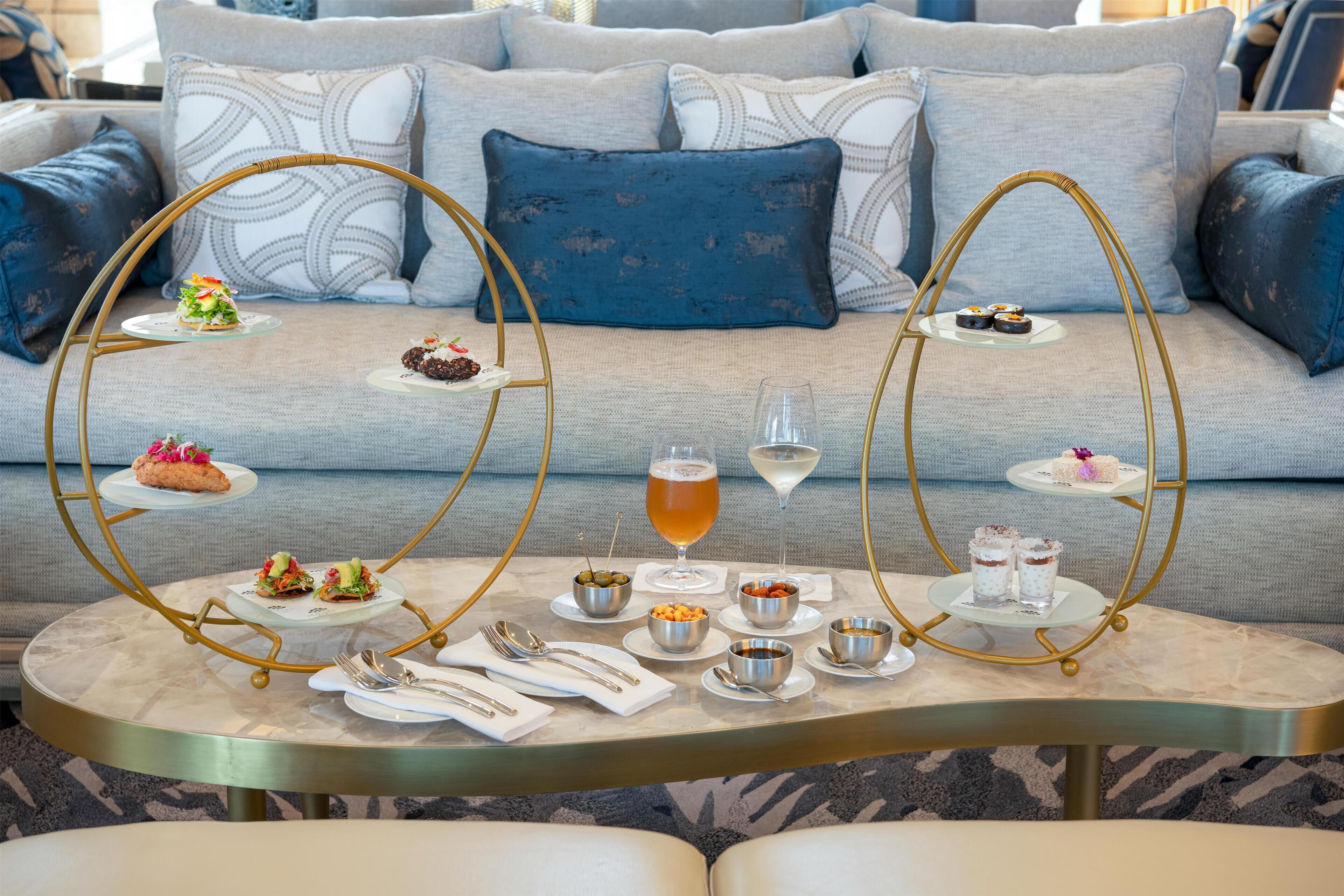 A dining table set with various dishes and drinks, surrounded by a sofa with patterned cushions.