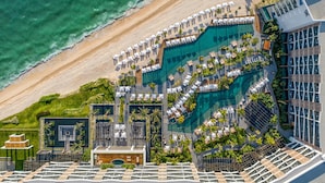 An aerial view of a resort with multiple swimming pools, sun loungers, and a beach. - Waldorf Astoria Riviera Maya (Cancun)