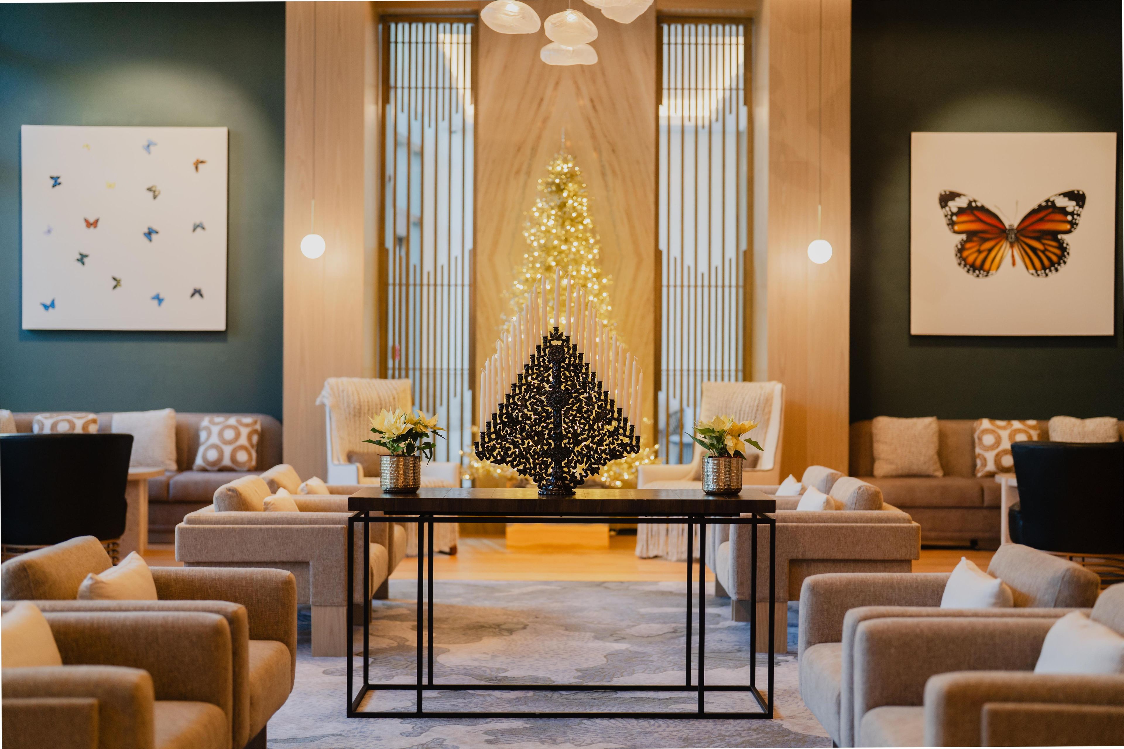 A cozy lobby with a central table, sofas, and a Christmas tree.