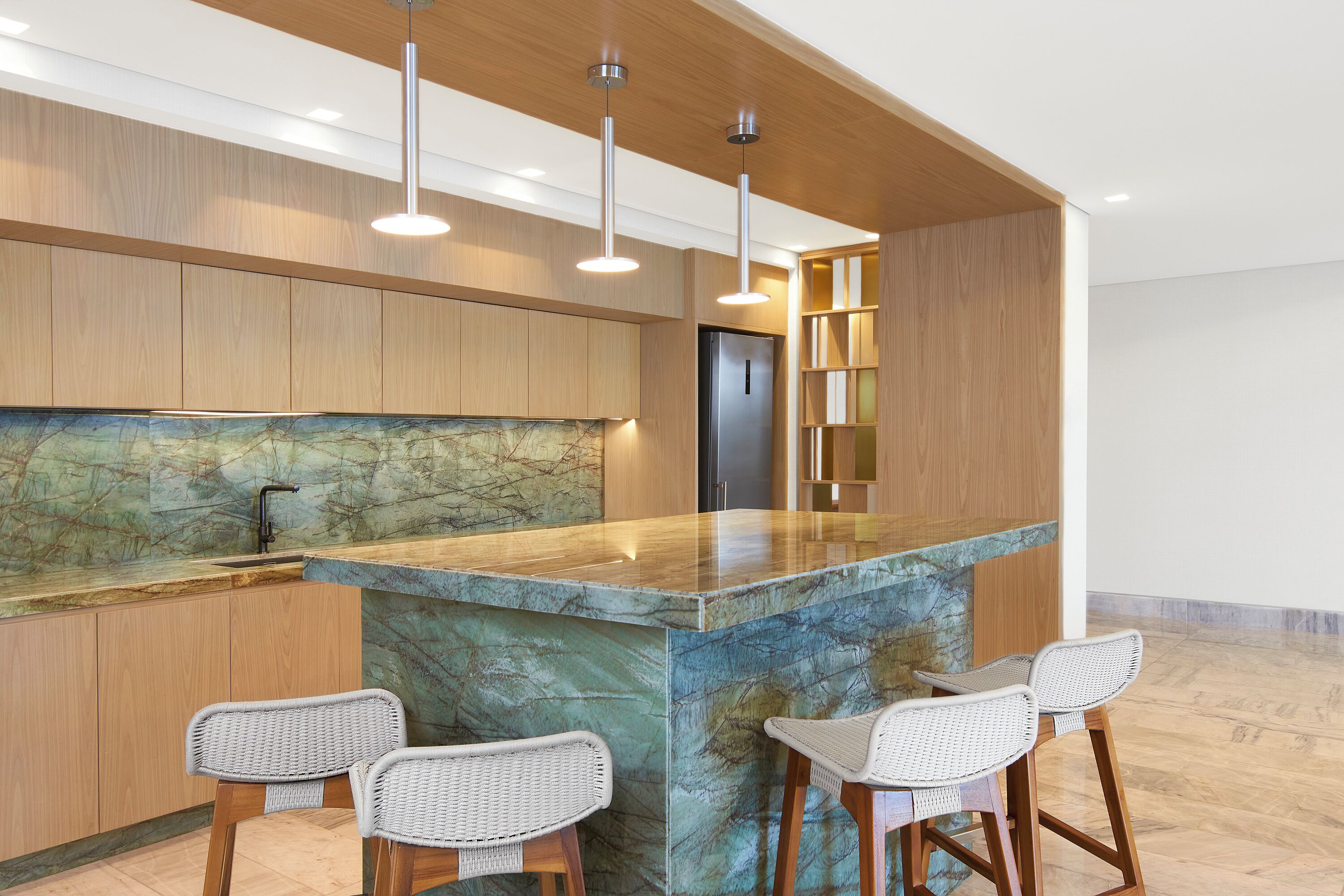 Een moderne keuken met een marmeren eiland, houten kastjes en barkrukken.