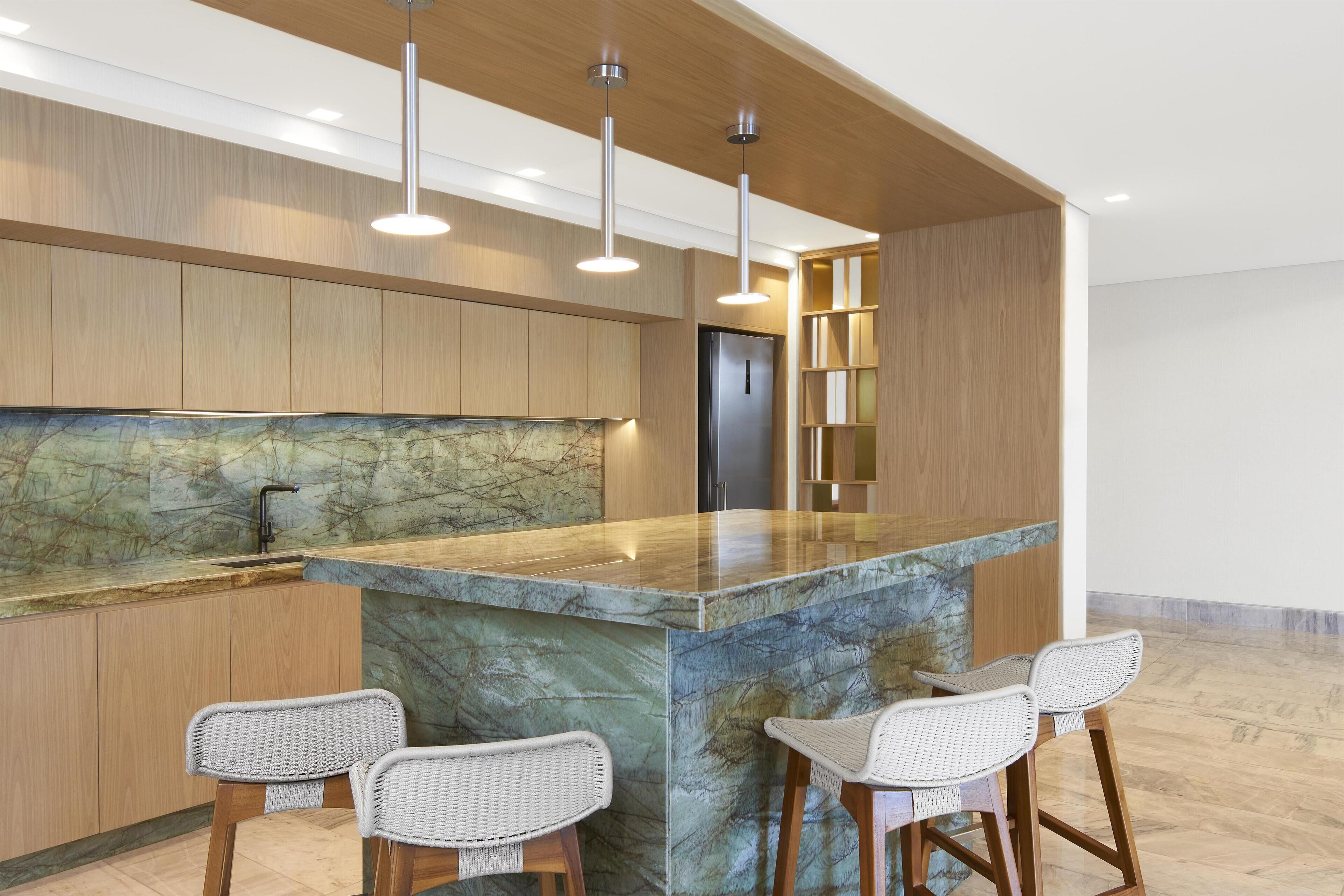 Una cocina moderna con una isla de mármol, armarios de madera y taburetes de bar.