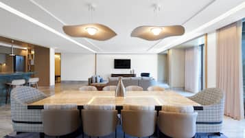 A modern dining area with a large table, six chairs, and pendant lighting.