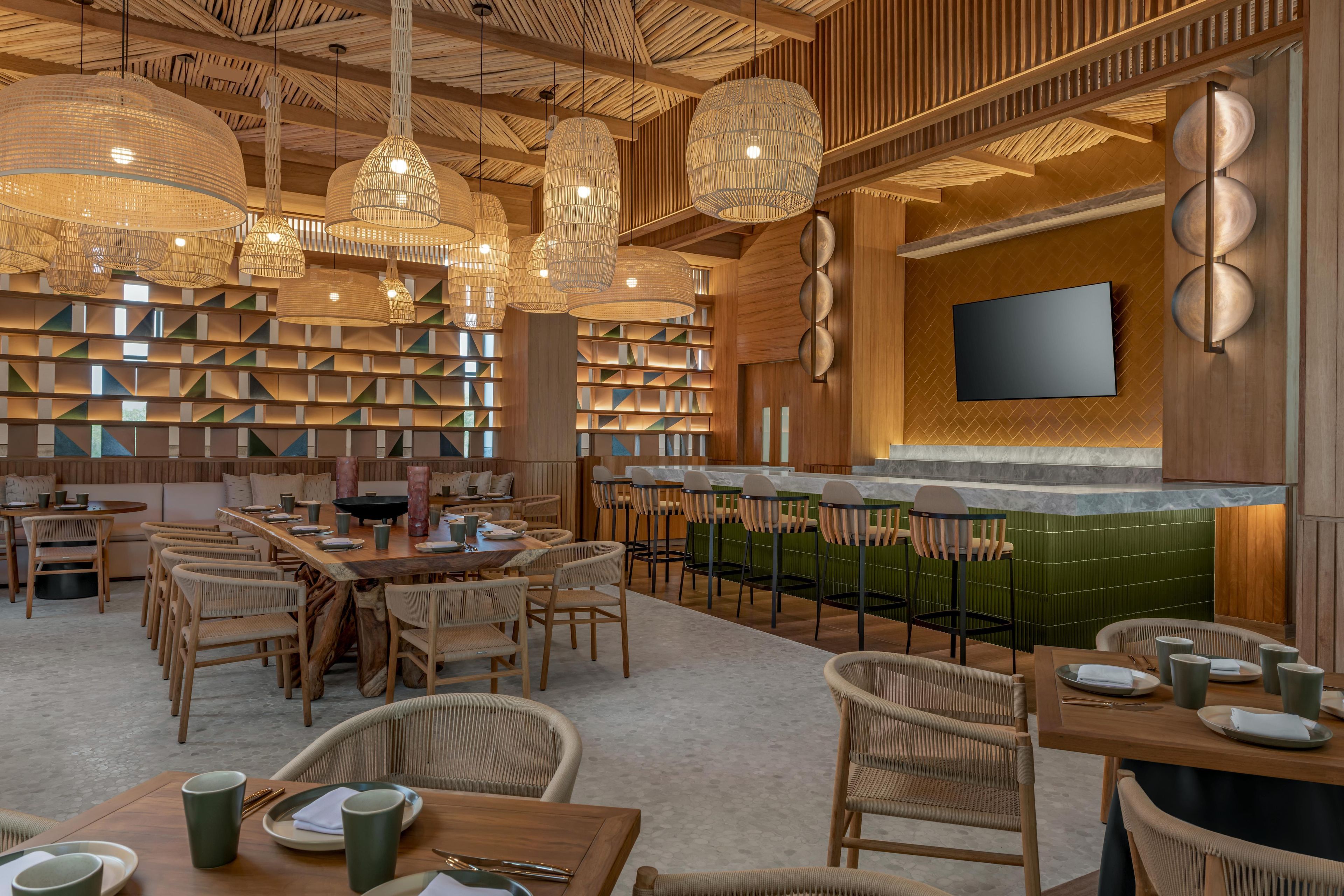 Een modern interieur met een bar, zitgedeeltes en een groot scherm aan de muur.