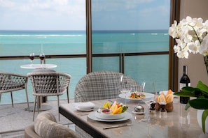 A dining area with a view of the ocean, featuring a table set with plates, glasses, and a bottle of wine. - Waldorf Astoria Riviera Maya, an All-Inclusive Experience (Cancun)