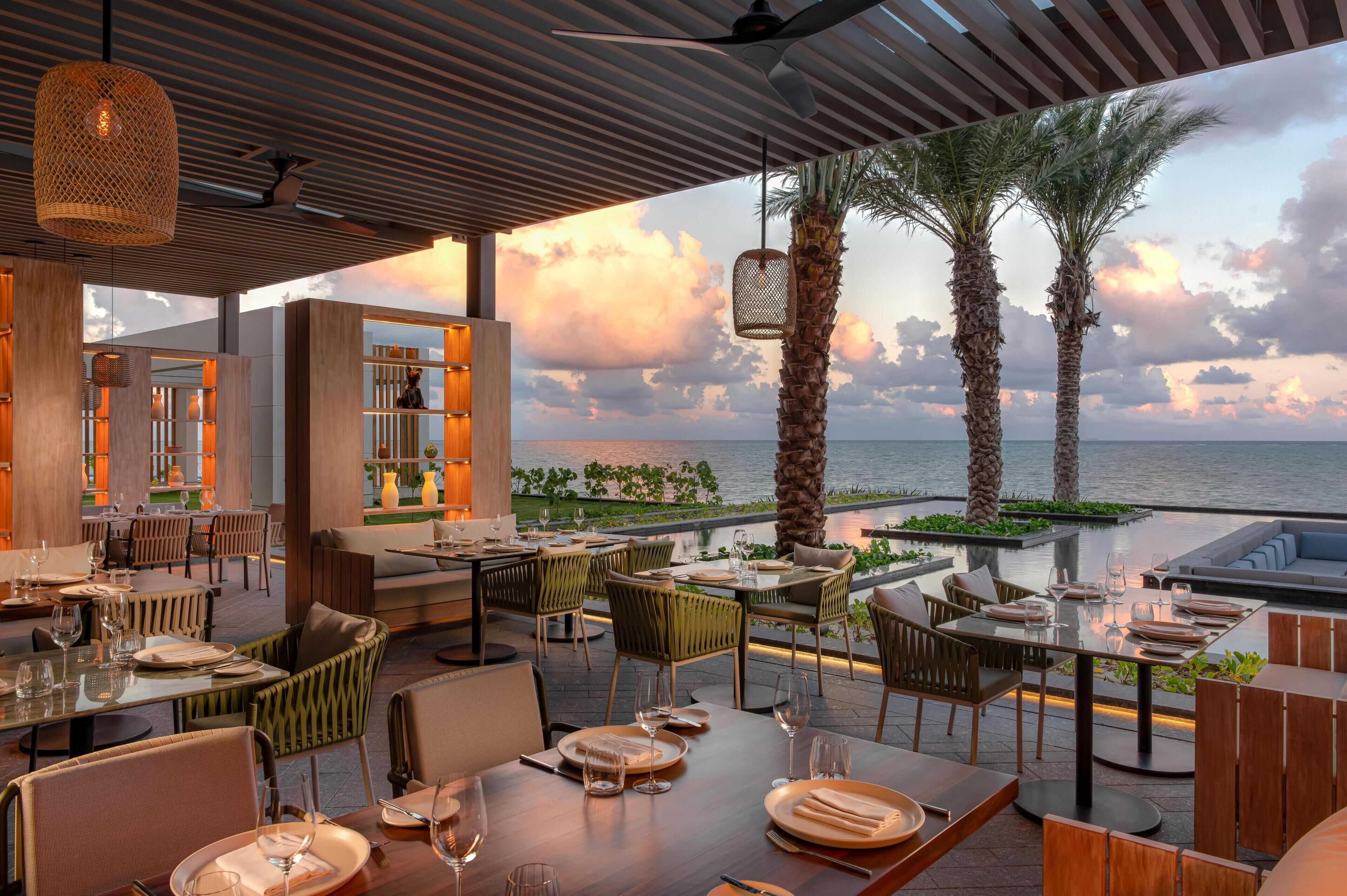 Un restaurant doté d’une terrasse offrant une vue sur la mer, avec un mobilier moderne et un panorama sur l’océan.