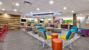 A modern hotel lobby with a seating area, a reception desk, and a children's play area. - Home2 Suites by Hilton Grand Blanc Flint (Grand Blanc)