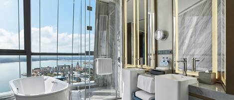Un baño moderno con una bañera grande, dos lavamanos y un espejo amplio.