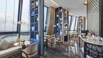 Un interno moderno con un'area bar, posti a sedere e vista attraverso ampie finestre.