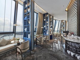 Un interior moderno con una zona de bar, asientos y vistas a través de amplios ventanales.