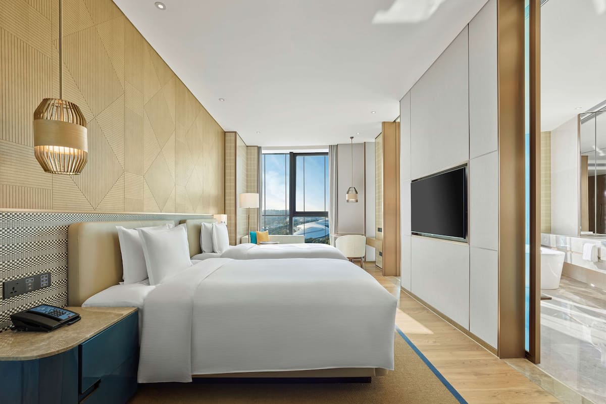 Una habitación de hotel moderna con una cama grande, televisión y vista a la ciudad.