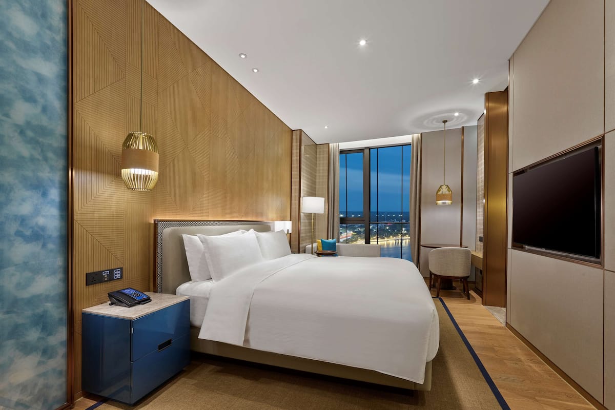 Habitación de hotel moderna con una cama grande, televisión y vista a la ciudad.