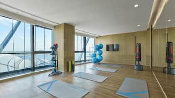 A spacious gym with exercise mats, a punching bag, and a wall-mounted TV.