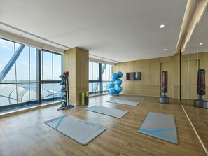 A spacious gym with exercise mats, a punching bag, and a wall-mounted TV. - Hilton Hainan Ocean Flower Island (Danzhou)