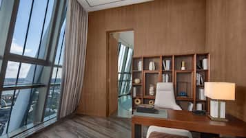 A modern office space with a large window, a desk, a chair, and a bookshelf.