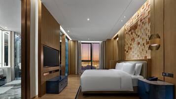 Ein modernes Hotelzimmer mit einem großen Bett, einem Flachbildfernseher, einer Wand mit Holzvertäfelung und Blick auf die Stadt.