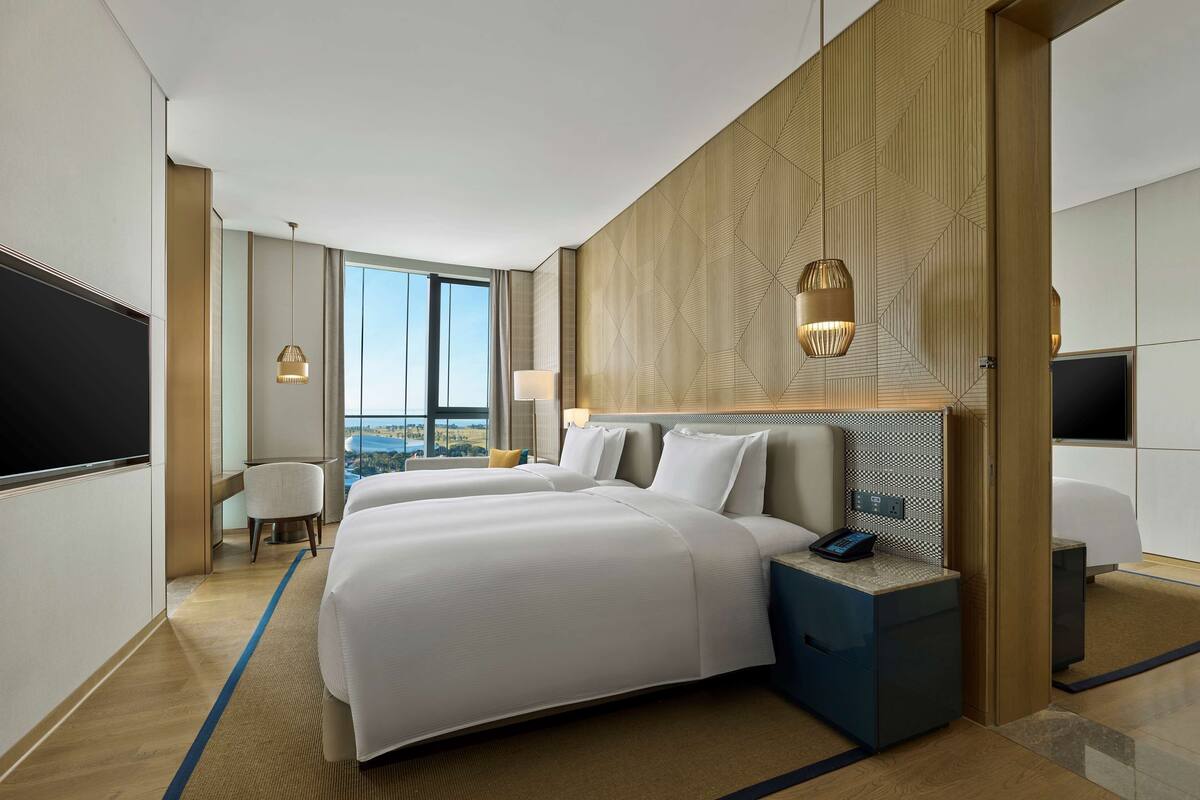 Una habitación de hotel moderna con una cama grande, un escritorio, una silla y un televisor.