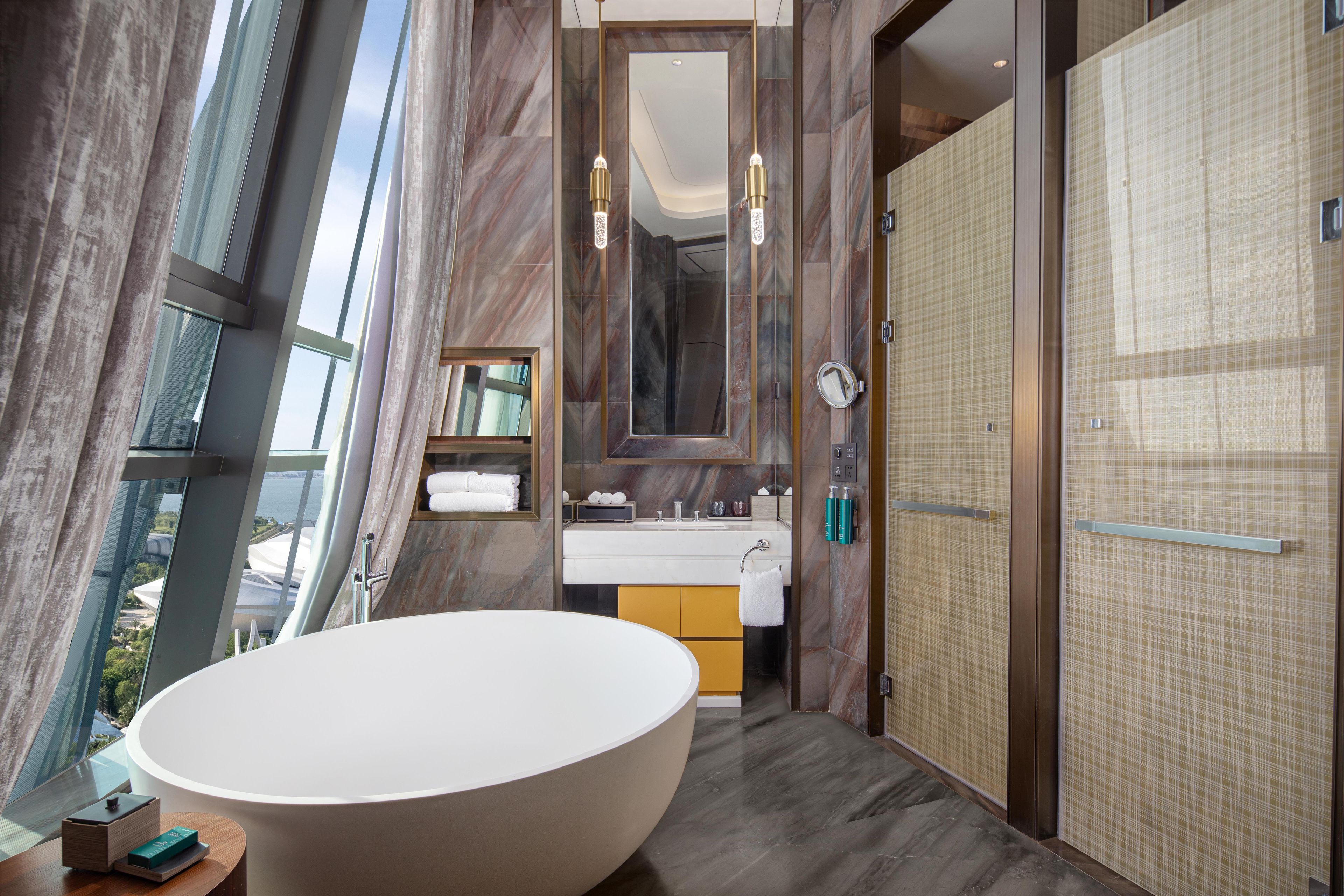 A modern bathroom with a large freestanding bathtub, a mirror above the sink, and a shower area.