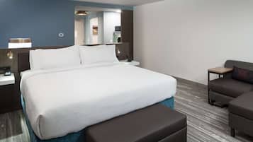 A hotel room with a large bed, a desk, a chair, and a sofa.