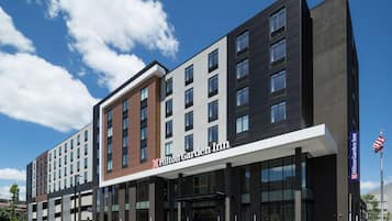 A modern hotel building with a prominent Hilton Garden Inn sign, multiple floors, and a parking lot.