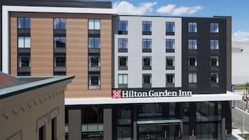 Een modern hotel met een opvallend Hilton Garden Inn bord, met een gevel van hout en metaal, grote ramen en een overdekte entree.