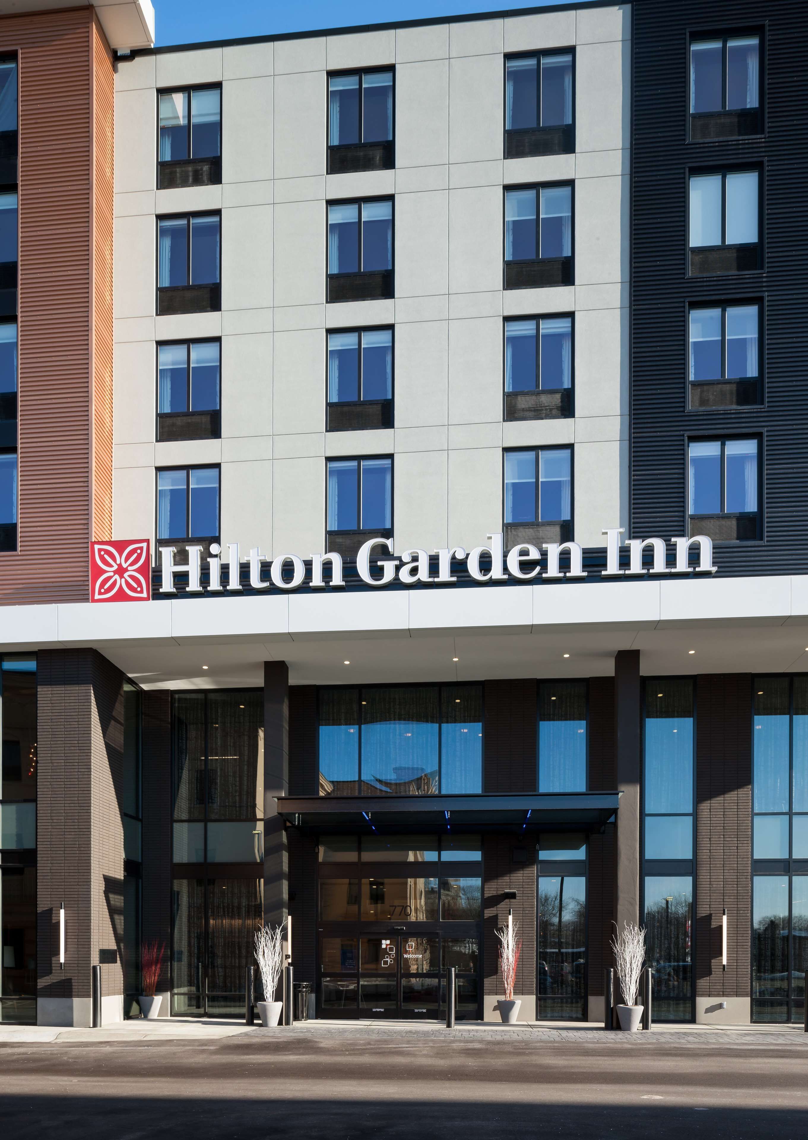 A modern hotel entrance with a clear sign reading "Hilton Garden Inn".