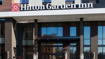 A modern hotel entrance with a clear sign reading "Hilton Garden Inn".