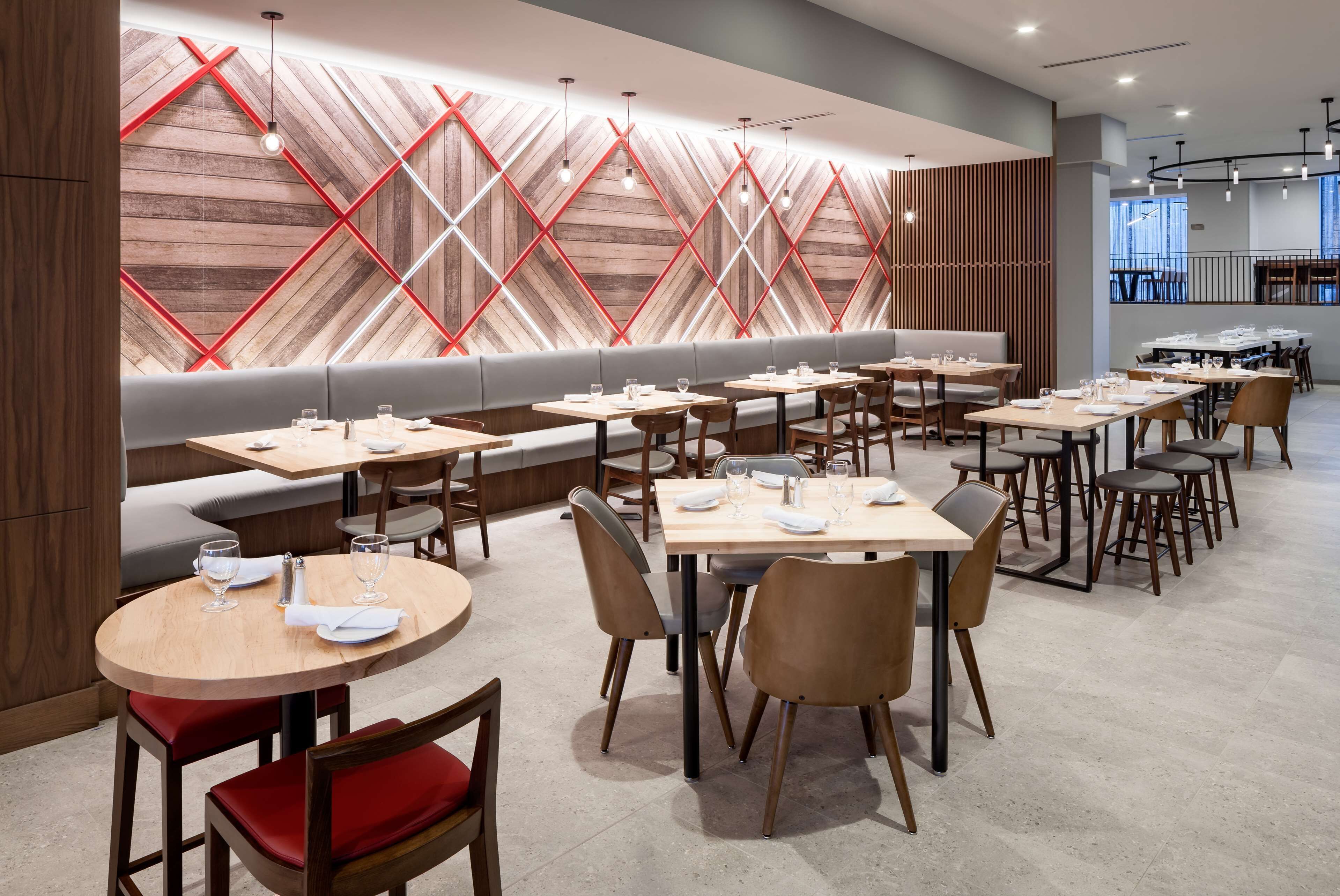 Un restaurante moderno con mesas redondas, mesas rectangulares y una zona de asientos con bancos largos.