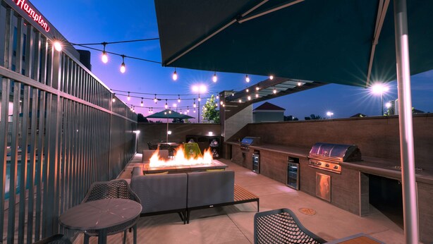 An outdoor patio with a grill, seating, and string lights. - Hampton Inn Riverside March Air Force Base (March Air Reserve Base)