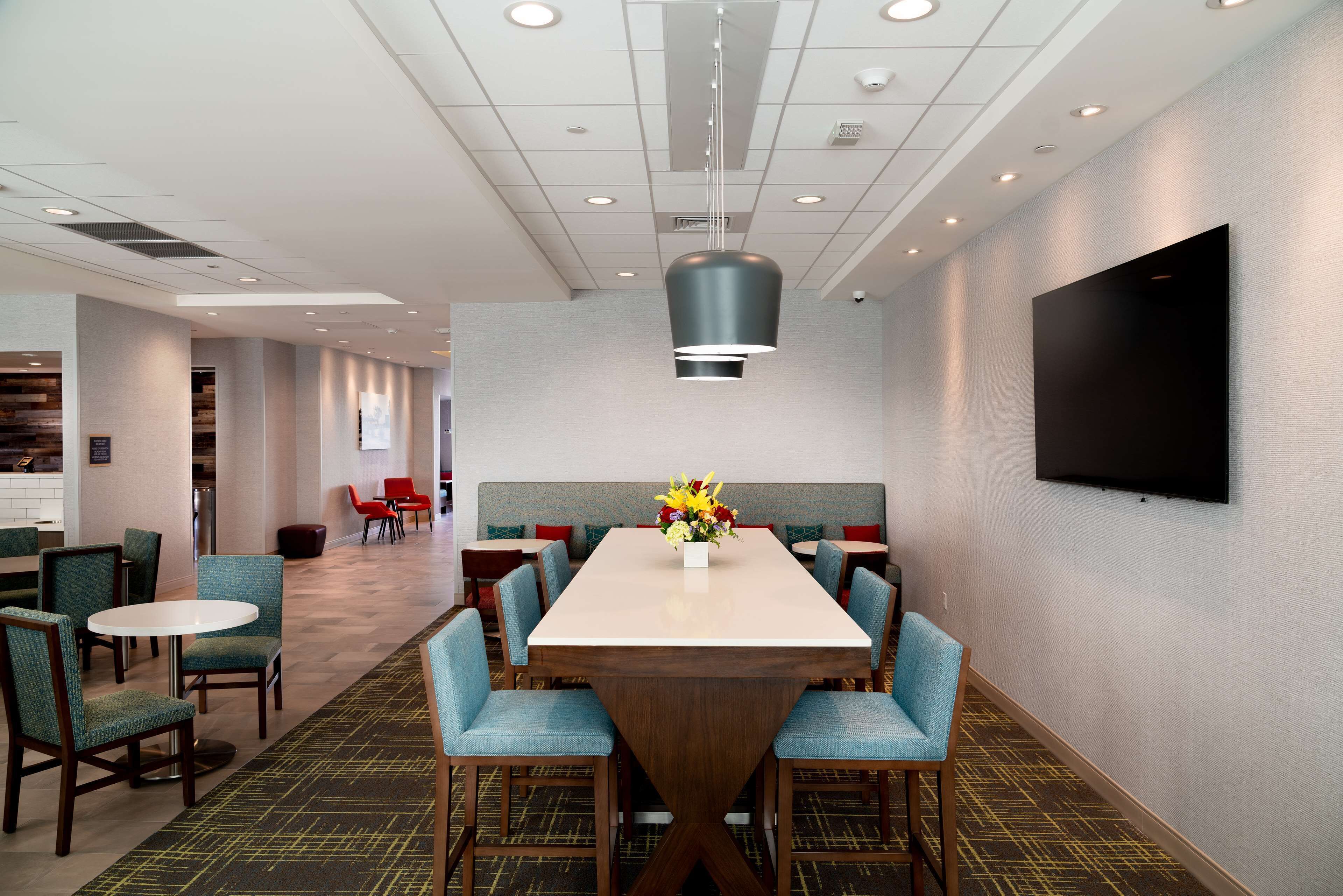 A hotel conference room with a large table, blue upholstered chairs, and a modern ceiling design.