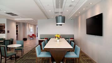 A hotel conference room with a large table, blue upholstered chairs, and a modern ceiling design.