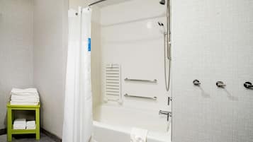 A bathroom with a bathtub, shower, and a green towel rack.