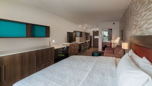 A modern hotel room with a large bed, a desk, a kitchenette, and a seating area. - Home2 Suites by Hilton Riverside March Air Force Base (March Air Reserve Base)