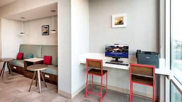 A modern workspace with a desk, two red chairs, a computer, and a printer.