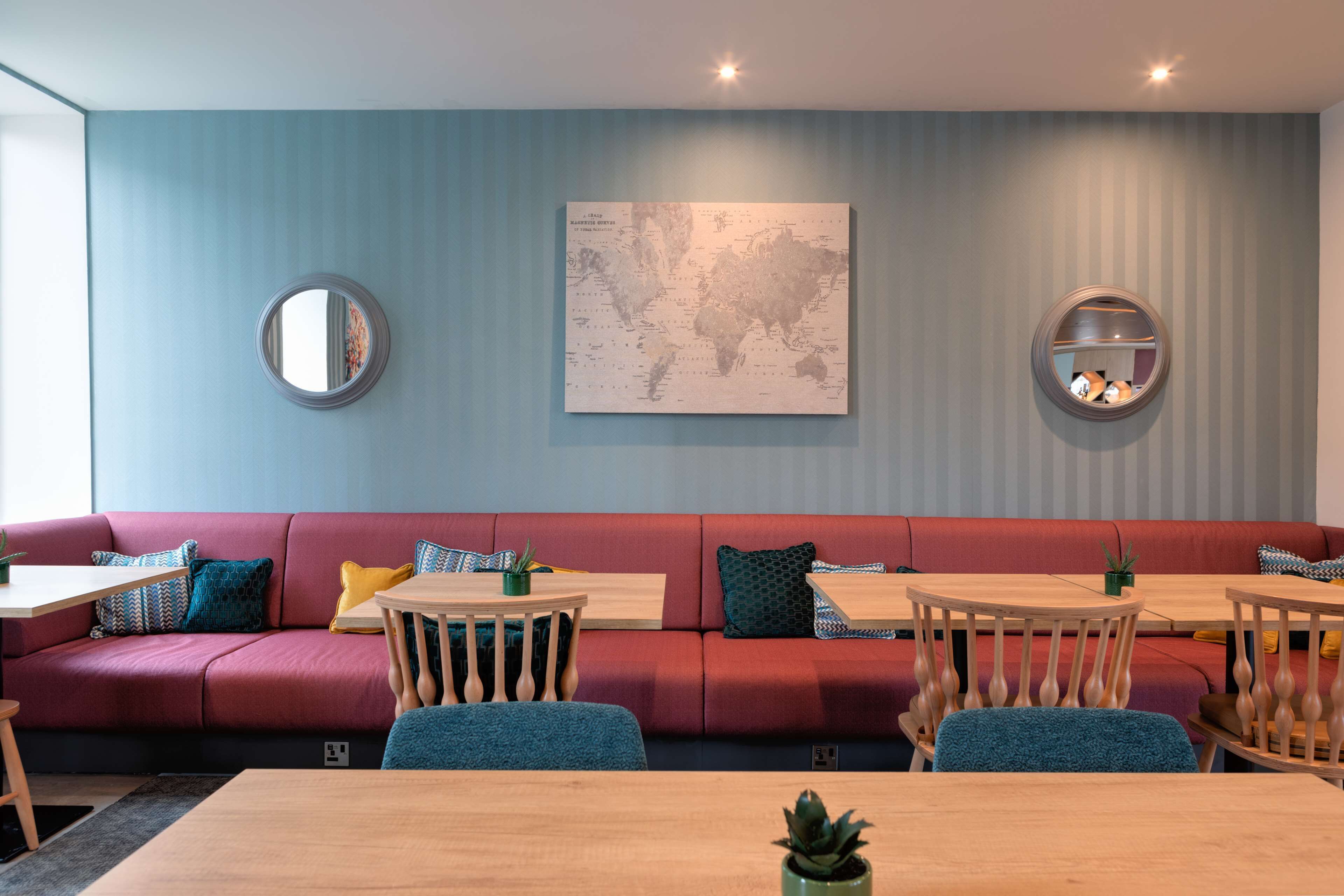 Un interior moderno con un sofá rojo, mesas de madera y un mapa mundial en la pared.