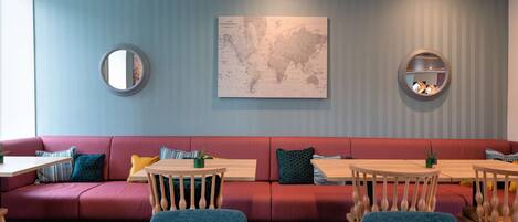 Un interior moderno con un sofá rojo, mesas de madera y un mapa mundial en la pared.