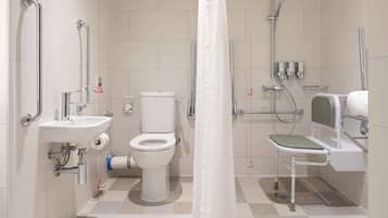 Un baño moderno con inodoro, lavabo, ducha y barras de apoyo.