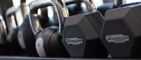 A row of black dumbbells with the brand "TECHNOGYM" on them.