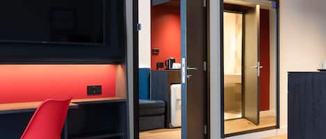 Una habitación de hotel moderna con una cama, un escritorio con una silla, un armario y una puerta que da a un baño.