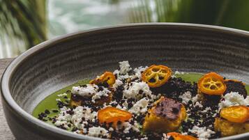 Un plato de comida con salsa verde, semillas negras y rodajas de naranja.