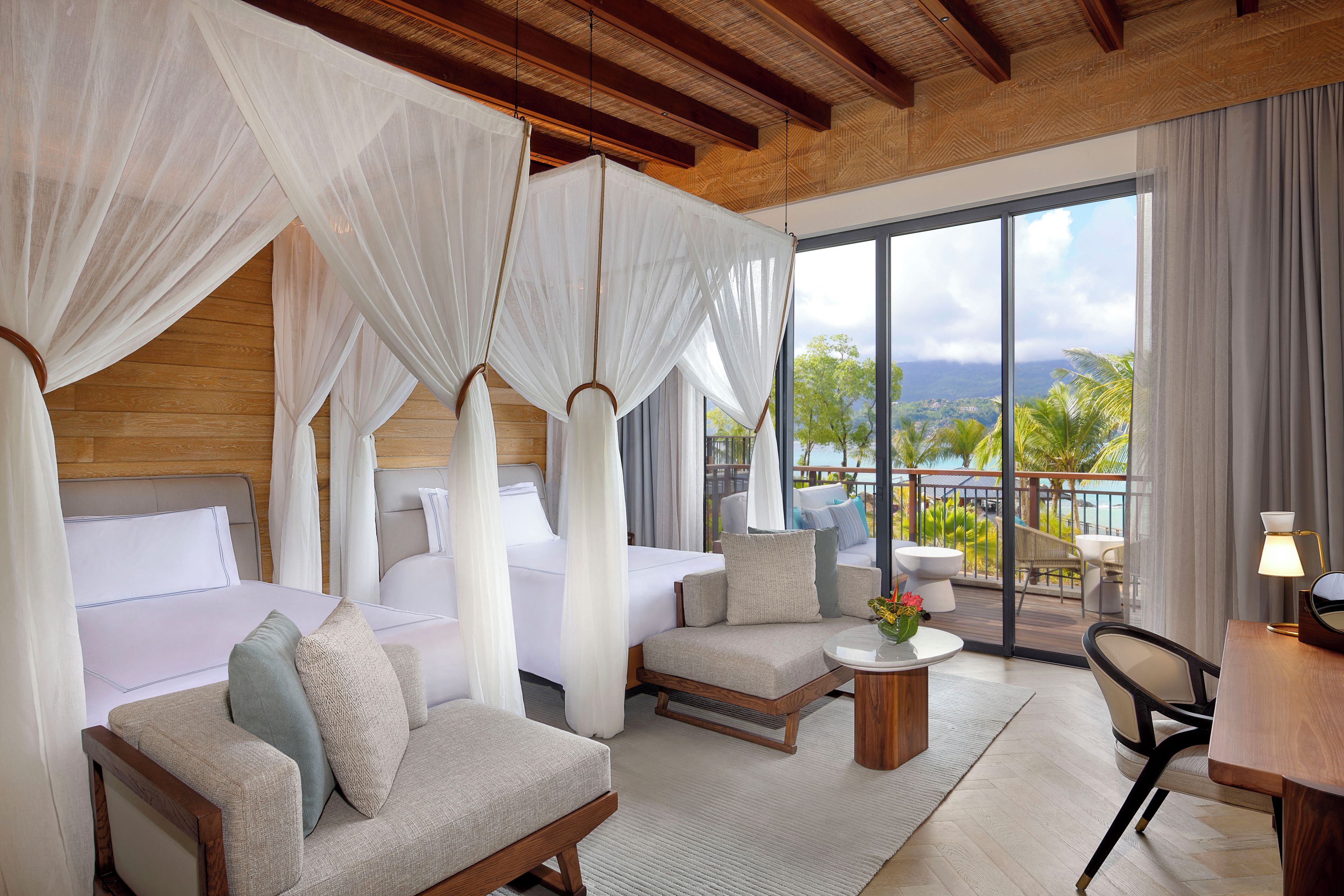 A hotel room with a balcony, a bed, a sofa, and a desk.