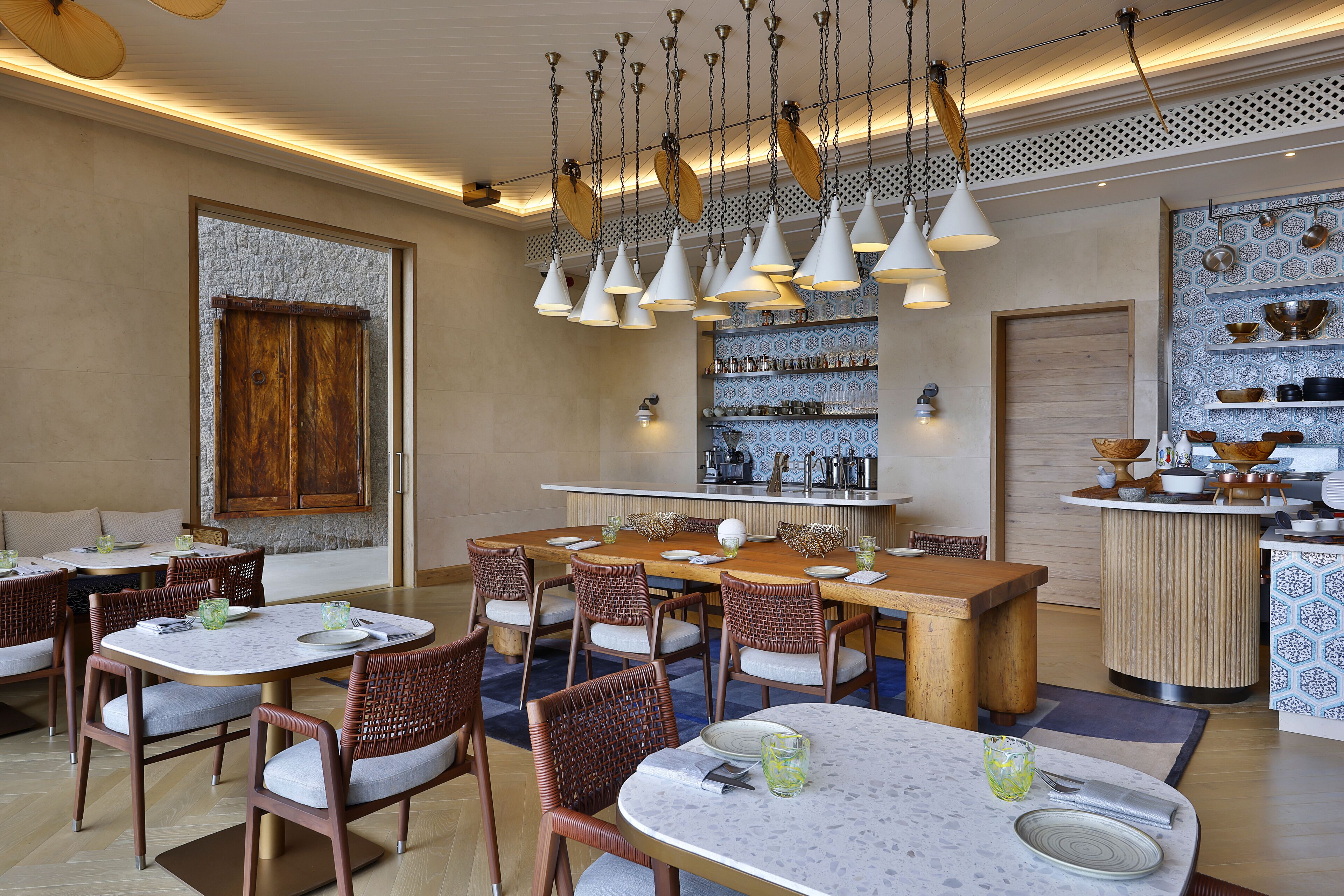 A restaurant with multiple dining tables and chairs, a bar area, and decorative lighting.