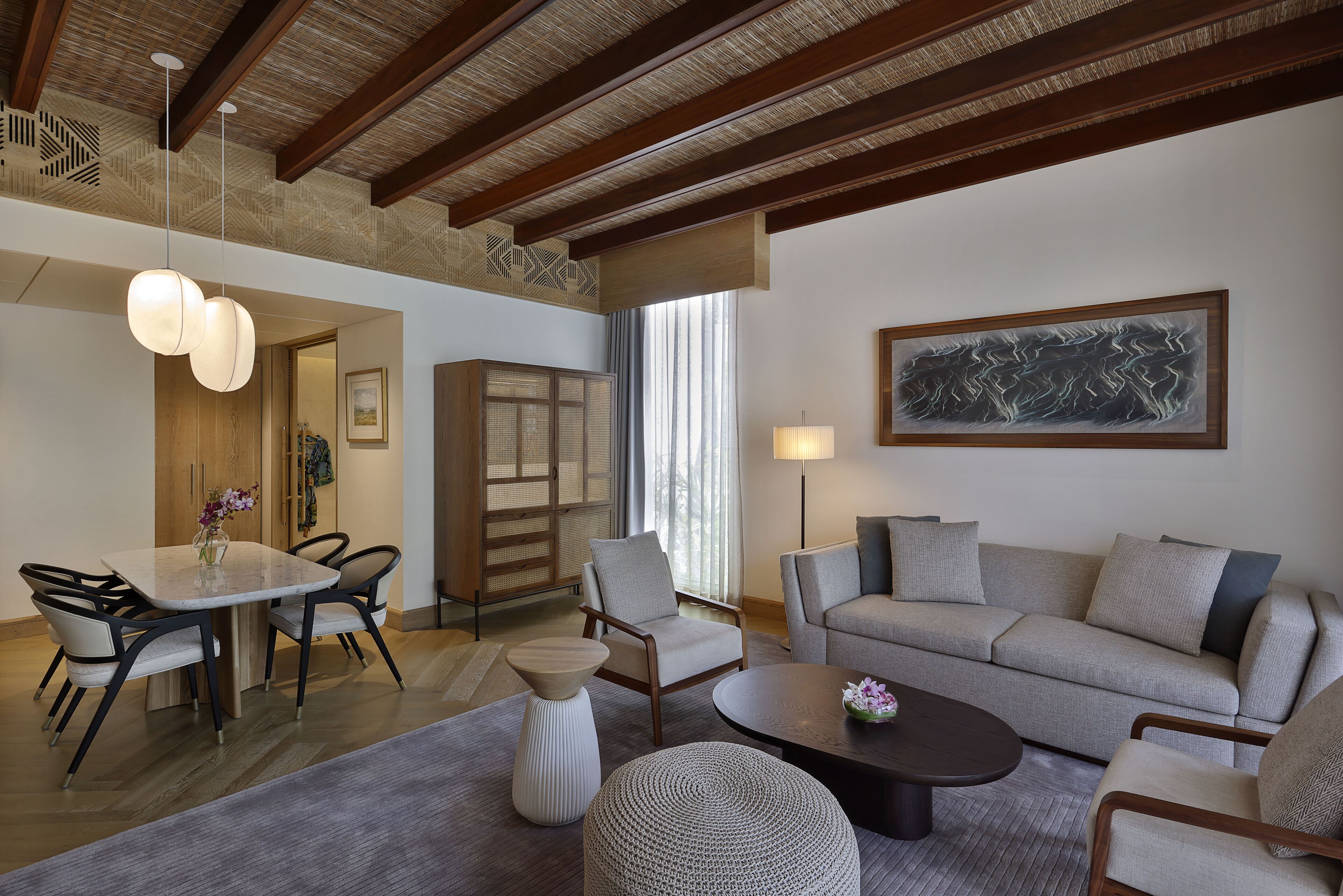 Una sala de estar moderna con comedor, que presenta techo de madera, un cuadro abstracto grande y un conjunto de sofá.