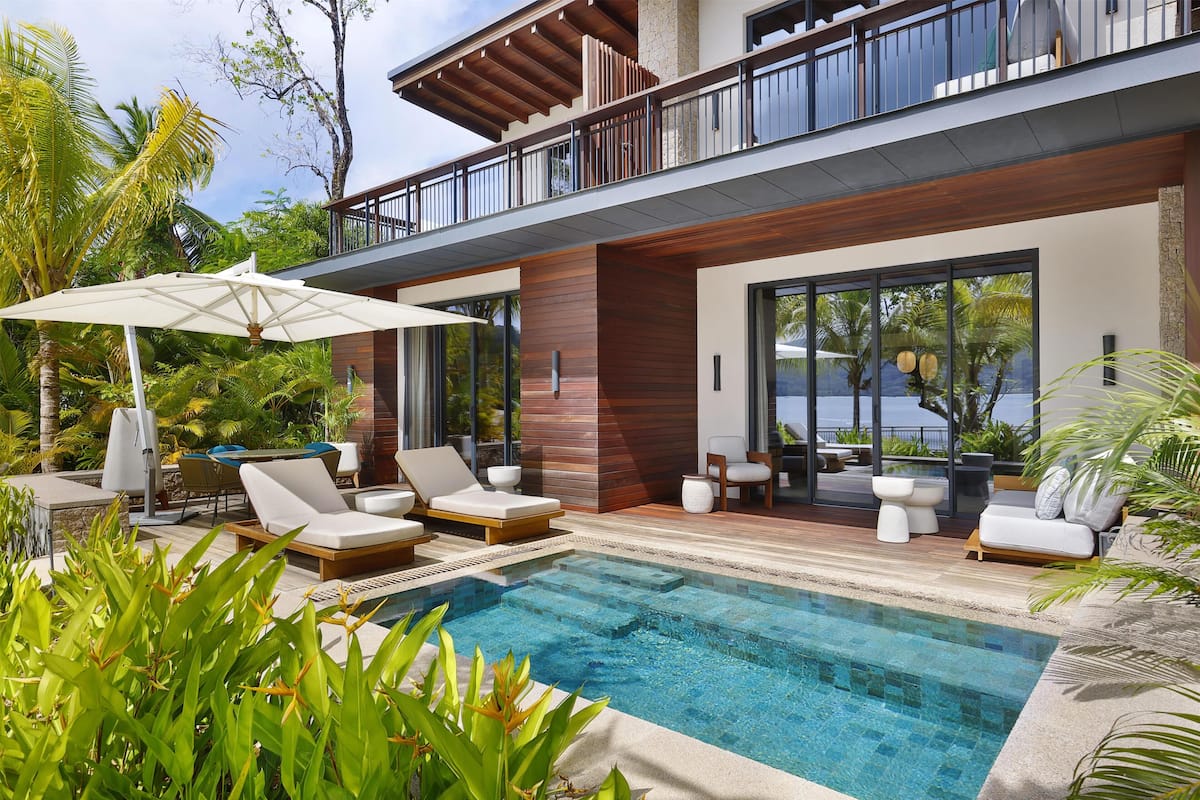 A modern poolside area with lounge chairs, a pool, and a balcony overlooking the ocean.