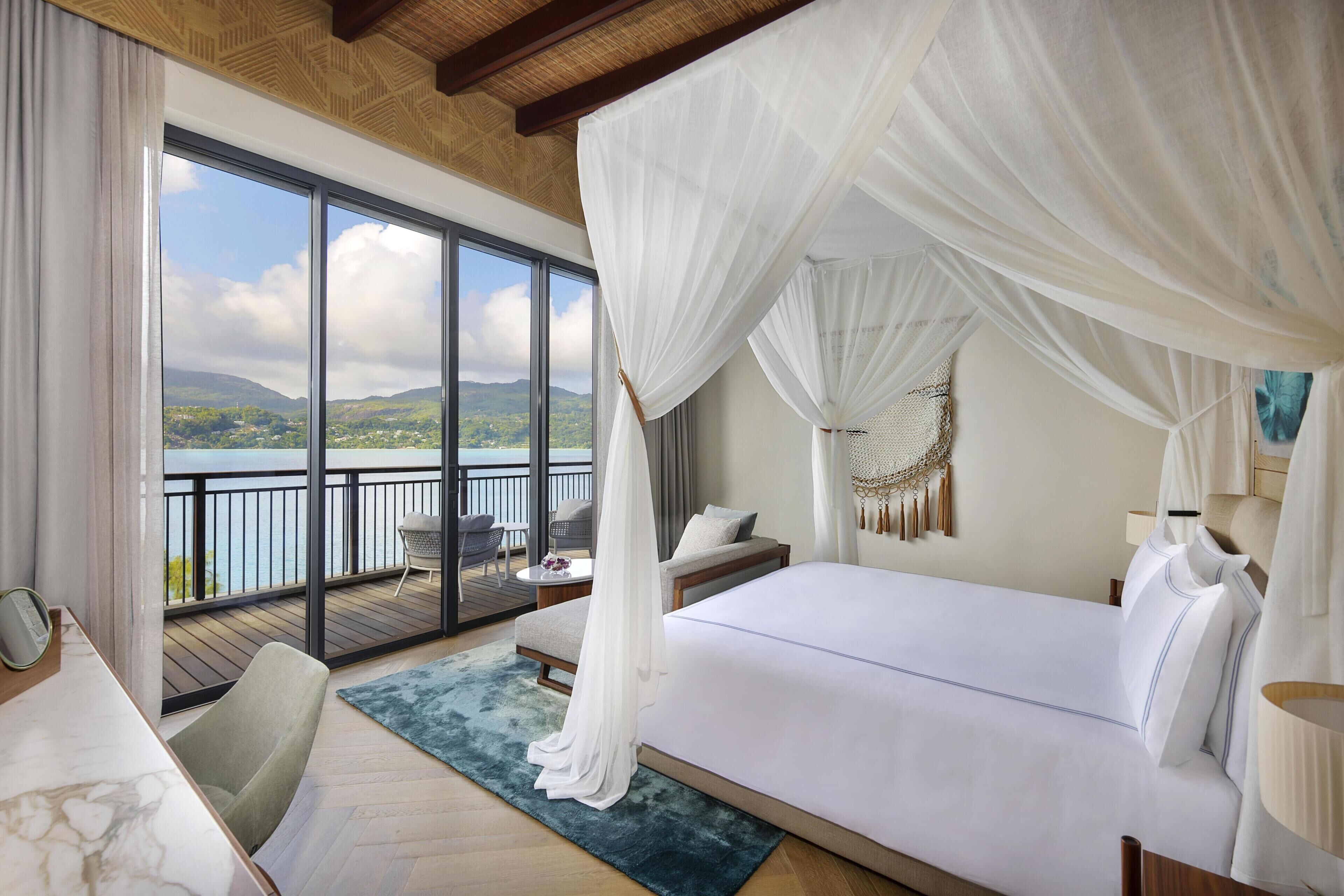 Un dormitorio con una cama grande, un balcón con vistas y techo de madera.