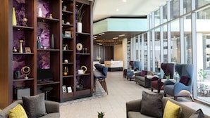 A modern lobby with a seating area, a bookshelf, and a large window. - DoubleTree by Hilton Tucson Downtown Convention Center (Tucson)